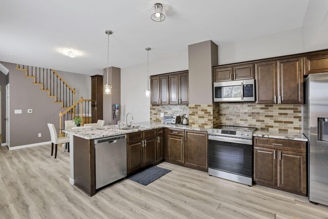 360 Hosack St, Columbus, OH 43207 - kitchen featuring light wood finished floors, a peninsula, dark brown cabinetry, and stainless steel appliances