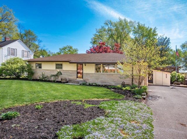 view of front of house with driveway, stone siding, a front lawn, entry steps, and stucco siding