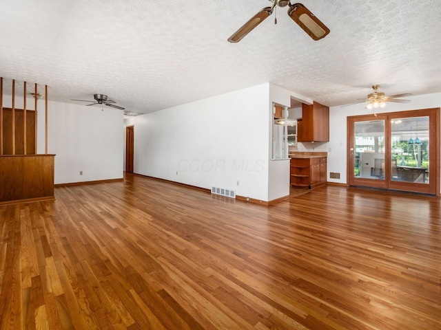 unfurnished living room featuring a ceiling fan, a textured ceiling, and visible vents