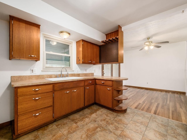 kitchen featuring a sink, ceiling fan, brown cabinets, and light countertops