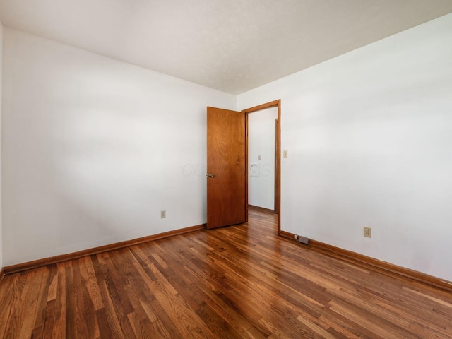 unfurnished room with baseboards and wood finished floors