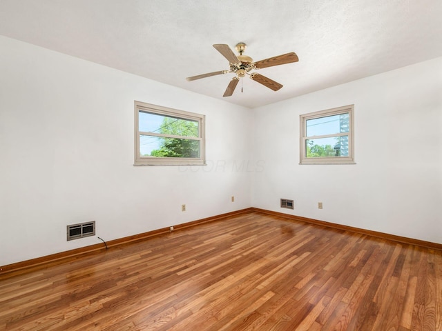 unfurnished room featuring visible vents, light wood-style floors, ceiling fan, and baseboards