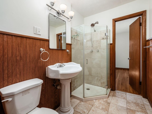 full bath featuring toilet, wood walls, a wainscoted wall, and a stall shower