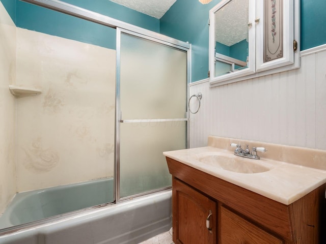 bathroom featuring wainscoting, bath / shower combo with glass door, and vanity