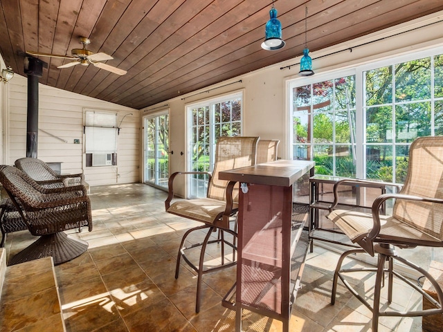 sunroom / solarium featuring ceiling fan, a wood stove, and cooling unit