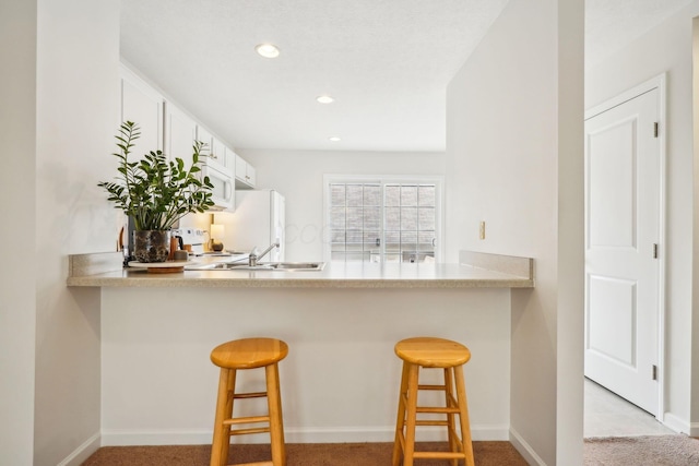 3857 Dowitcher Ln, Columbus, OH 43230 - kitchen featuring a peninsula, a breakfast bar area, recessed lighting, a sink, and baseboards