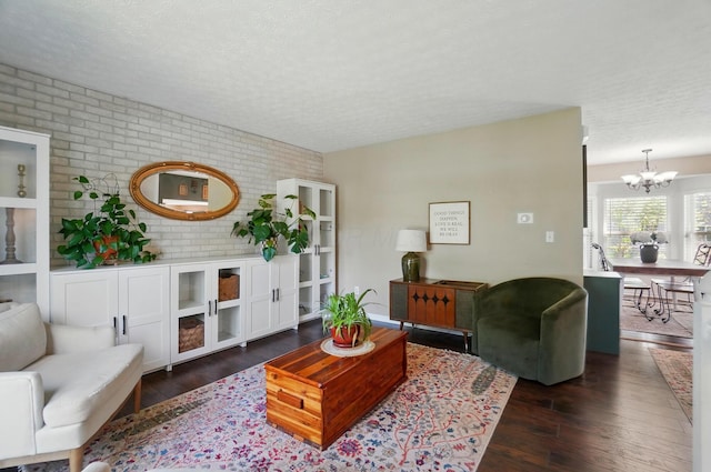 5694 Danmar Dr, Canal Winchester, OH 43110 - living room featuring brick wall, a textured ceiling, dark wood-style flooring, and a chandelier