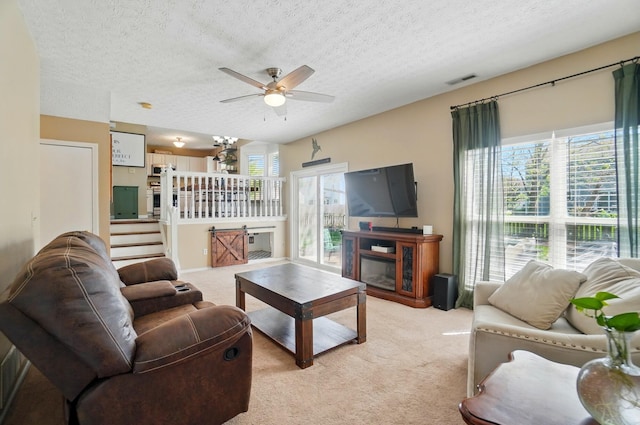5694 Danmar Dr, Canal Winchester, OH 43110 - living room with light colored carpet, a ceiling fan, a textured ceiling, and a glass covered fireplace