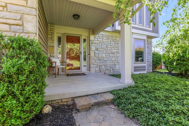 entrance to property featuring covered porch and stone siding