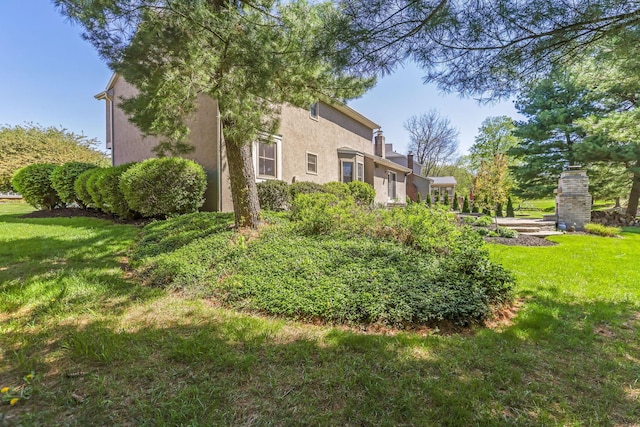 view of side of home with a yard and stucco siding