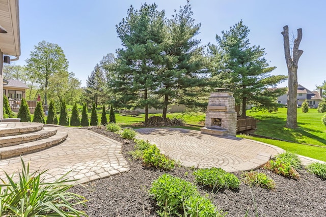 view of yard with a patio and an outdoor stone fireplace