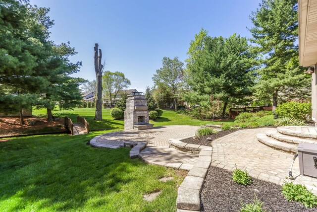 view of yard with a patio and an outdoor stone fireplace