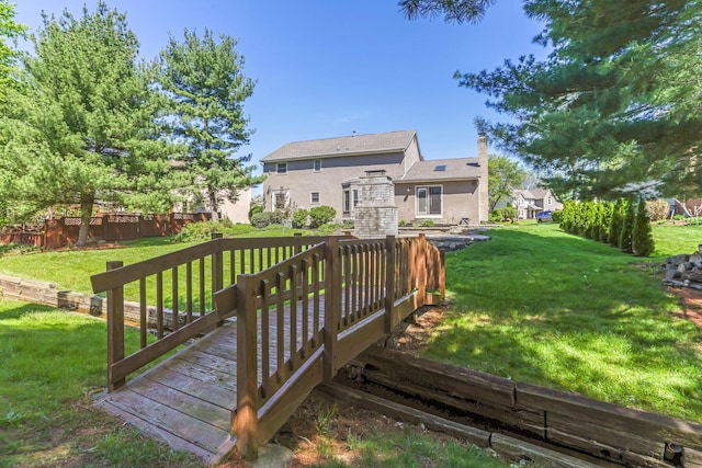 wooden terrace featuring fence and a yard