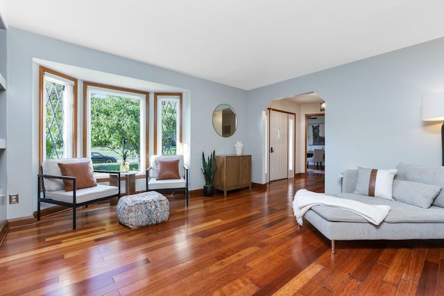 living room featuring arched walkways, hardwood / wood-style floors, and baseboards