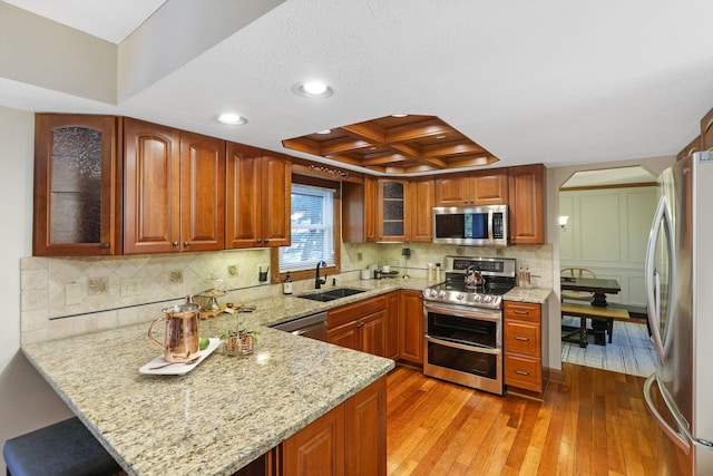 kitchen featuring recessed lighting, coffered ceiling, appliances with stainless steel finishes, a sink, and a peninsula