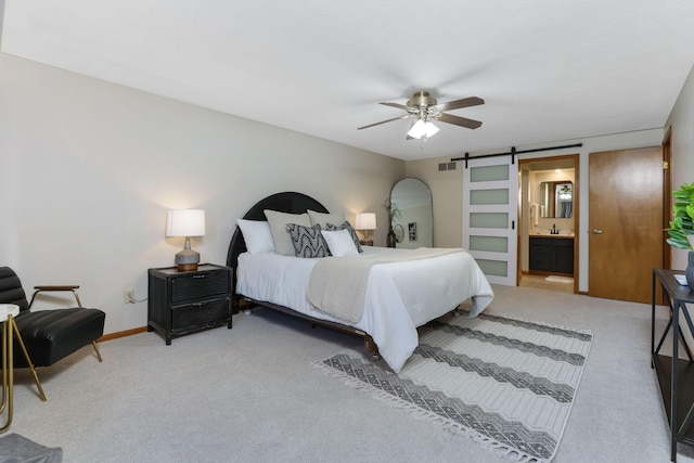 bedroom with a barn door, connected bathroom, visible vents, and carpet floors