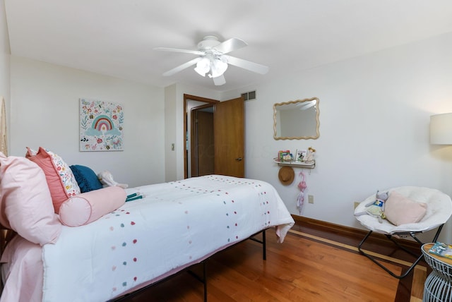 bedroom featuring wood finished floors, a ceiling fan, visible vents, and baseboards