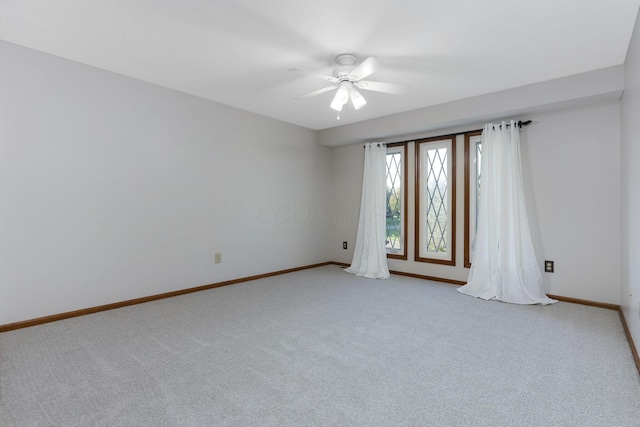 empty room with a ceiling fan, light carpet, and baseboards