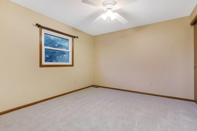 empty room with baseboards, a ceiling fan, visible vents, and light carpet