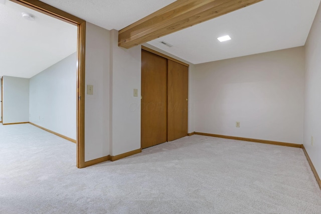 basement with baseboards, visible vents, and light carpet