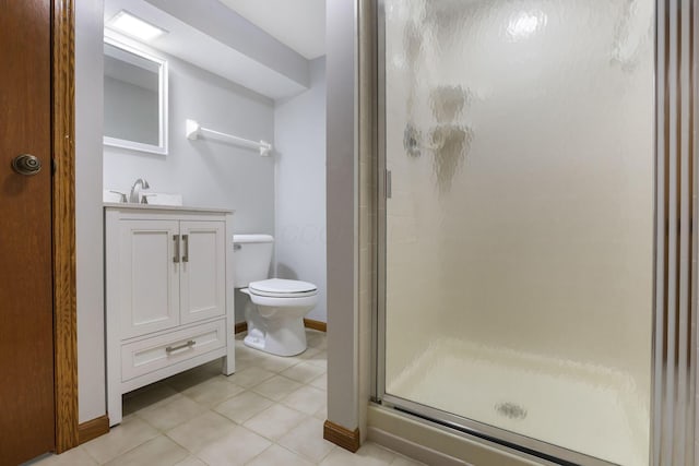 bathroom featuring tile patterned flooring, a shower stall, toilet, vanity, and baseboards