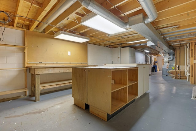 unfinished basement with a workshop area, heating unit, and concrete block wall