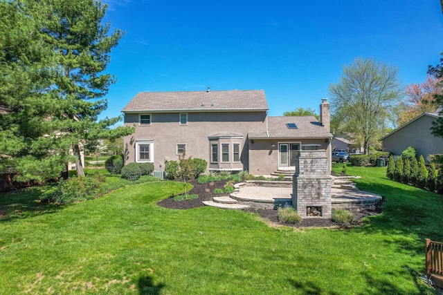 back of house with stucco siding, a chimney, and a yard