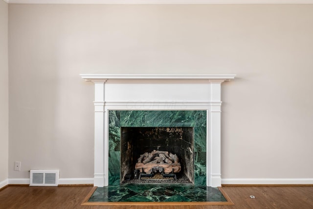 details with visible vents, baseboards, wood finished floors, and a tiled fireplace