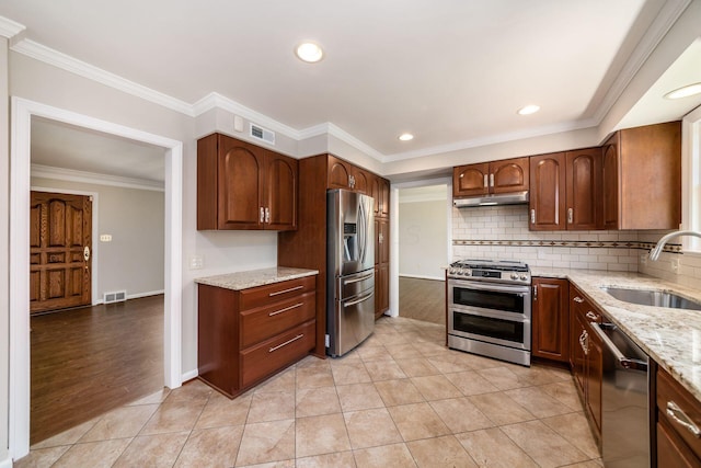 kitchen featuring visible vents, under cabinet range hood, light stone counters, a sink, and appliances with stainless steel finishes