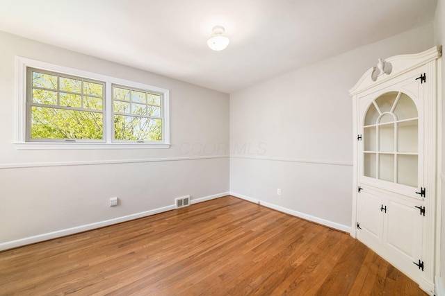 empty room featuring baseboards, visible vents, and light wood-style flooring