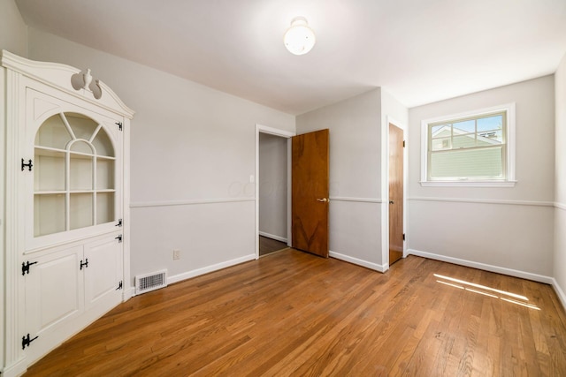 empty room with baseboards, visible vents, and wood finished floors