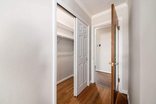 corridor with baseboards, ornamental molding, and wood finished floors