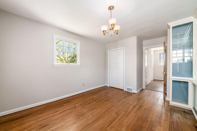 interior space with an inviting chandelier, baseboards, hardwood / wood-style floors, and visible vents