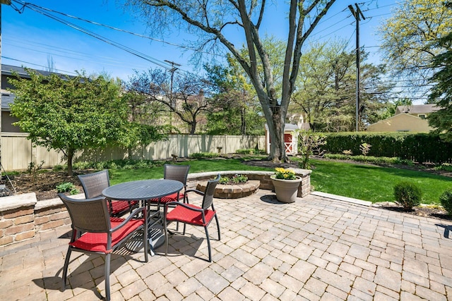 view of patio featuring outdoor dining area, a fenced backyard, a storage shed, and an outdoor structure