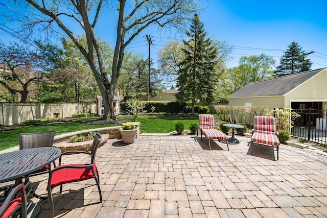 view of patio featuring a fenced backyard, a storage unit, an outdoor structure, and outdoor dining area