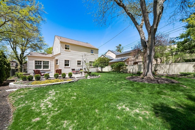 rear view of property with fence, a patio, and a lawn