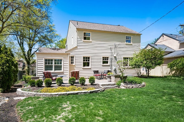 rear view of property featuring a lawn, a patio, fence, and roof with shingles