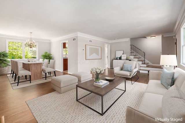 living room featuring visible vents, crown molding, wood finished floors, an inviting chandelier, and stairs