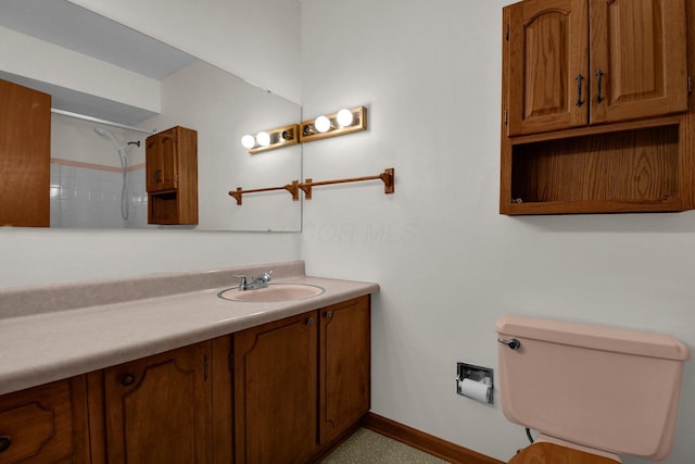 bathroom featuring toilet, baseboards, walk in shower, and vanity