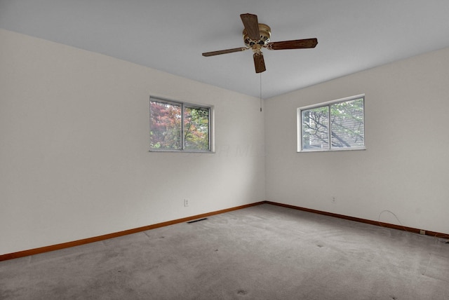 carpeted spare room with baseboards, a ceiling fan, and visible vents