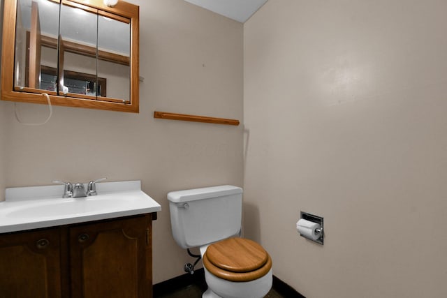 half bathroom with toilet, baseboards, and vanity