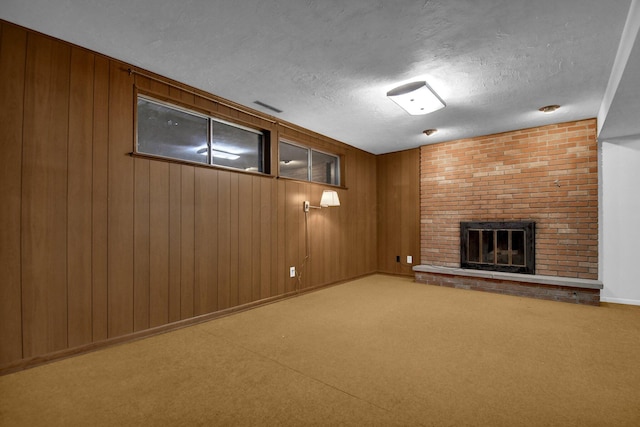 finished basement featuring carpet, a brick fireplace, wood walls, and a textured ceiling