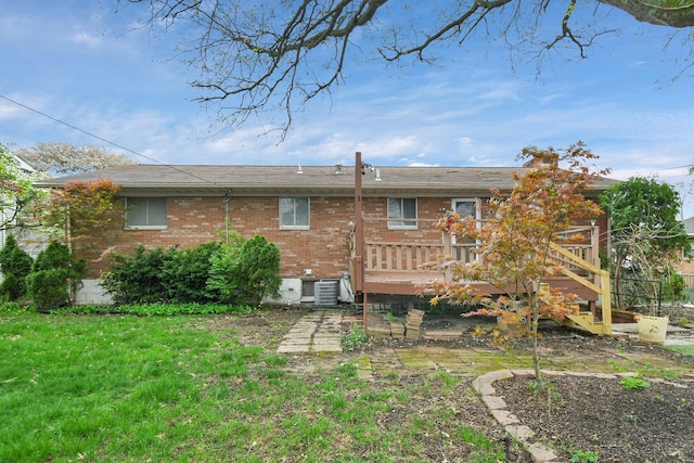 back of house featuring brick siding, a lawn, a wooden deck, and cooling unit