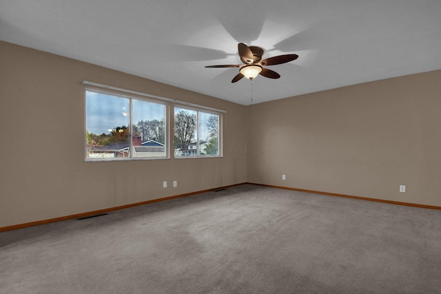 carpeted spare room with baseboards and a ceiling fan