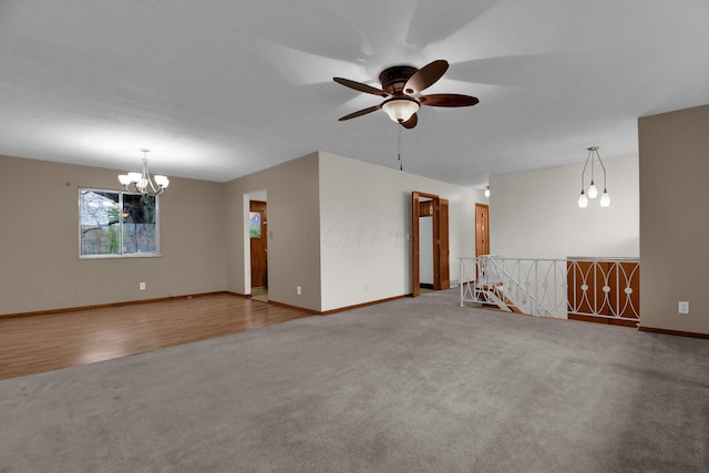 empty room featuring baseboards, carpet, and ceiling fan with notable chandelier