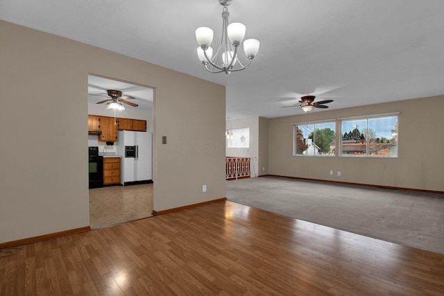 unfurnished living room featuring baseboards, light wood finished floors, and ceiling fan with notable chandelier