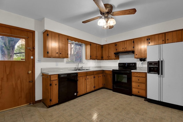 kitchen featuring a sink, light countertops, black appliances, and under cabinet range hood