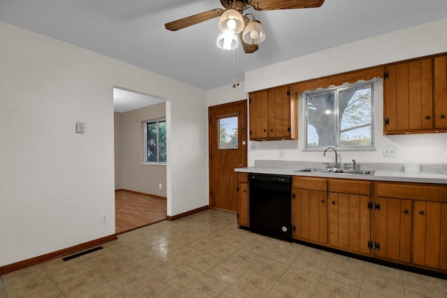 kitchen with ceiling fan, a sink, light countertops, brown cabinetry, and black dishwasher