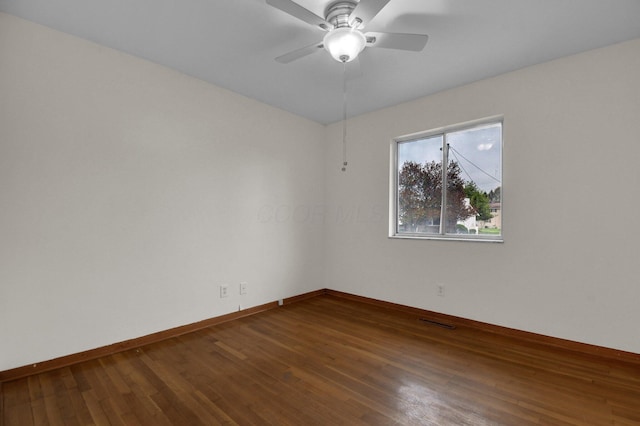 empty room featuring baseboards, a ceiling fan, visible vents, and hardwood / wood-style flooring