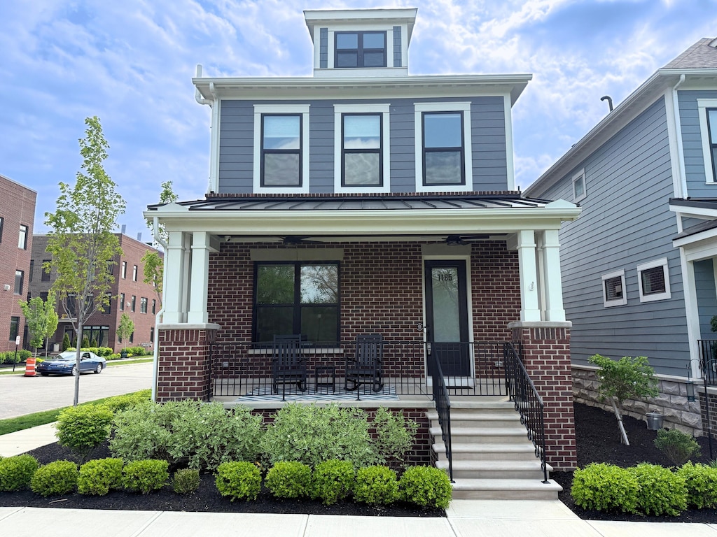 american foursquare style home featuring covered porch and brick siding